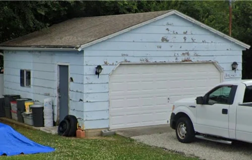 A detached garage before the work: worn roof, peeling paint and rotted trim