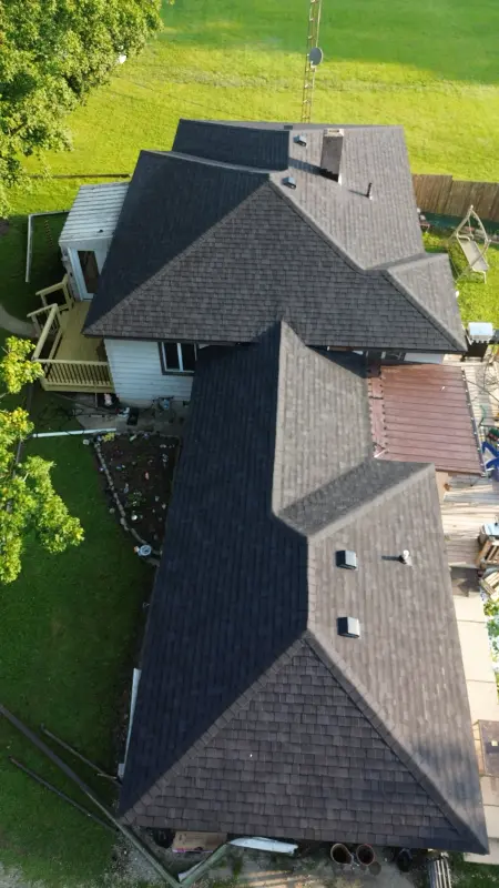 Dark architectural shingle roof across an L-shaped ranch home, seen from above