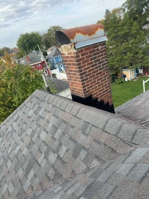Brick chimney with flashing transition and new shingles below in Piqua