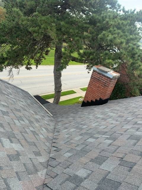 Completed architectural shingle roof with chimney penetration and clean flashing detail in Piqua